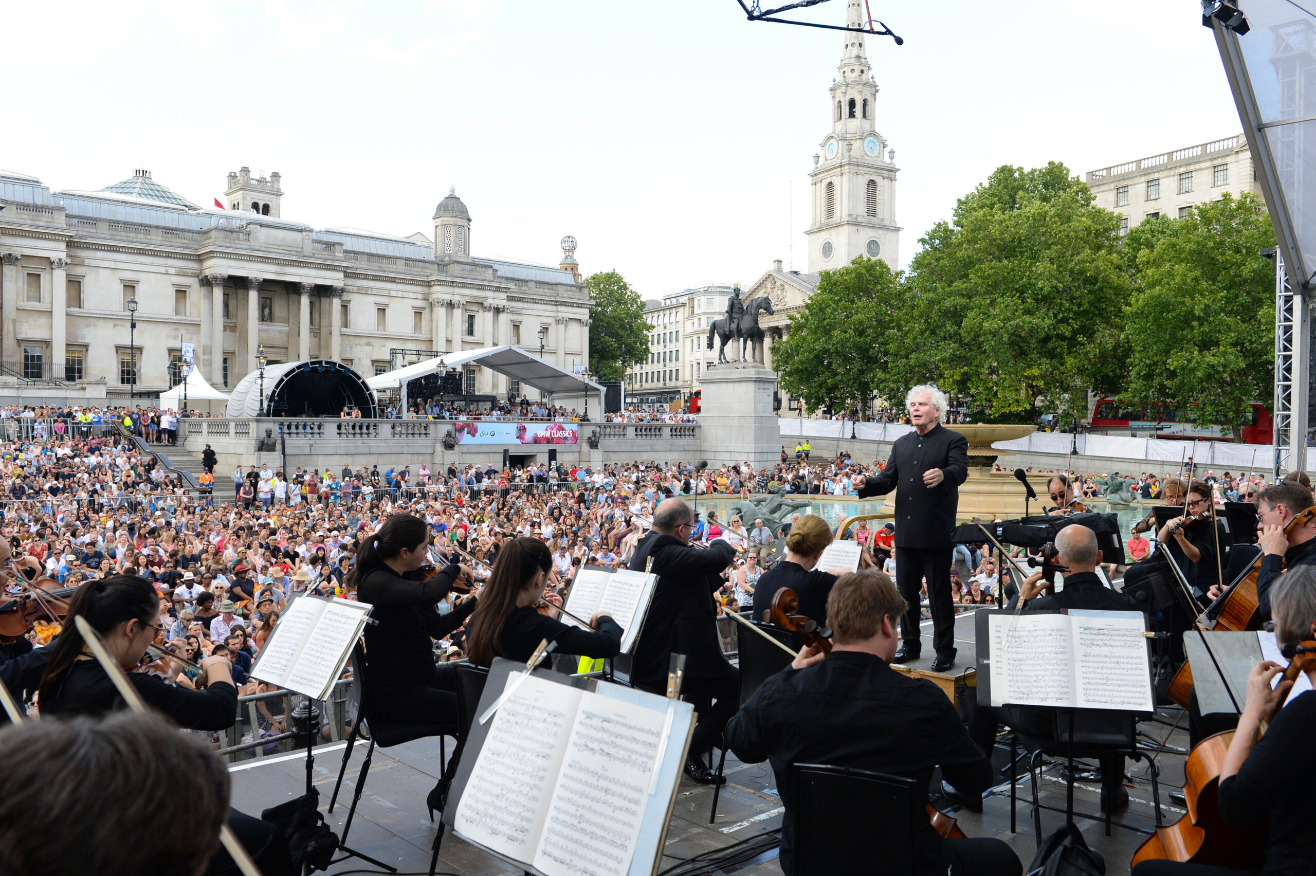 Conductor Sir Simon Rattle conducts the LSO in Trafalgar Square London