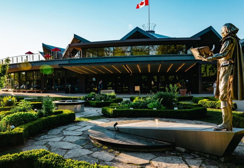 View of the outside of the Stratford Festival theatre main building with a statue of William Shakespeare in the foreground