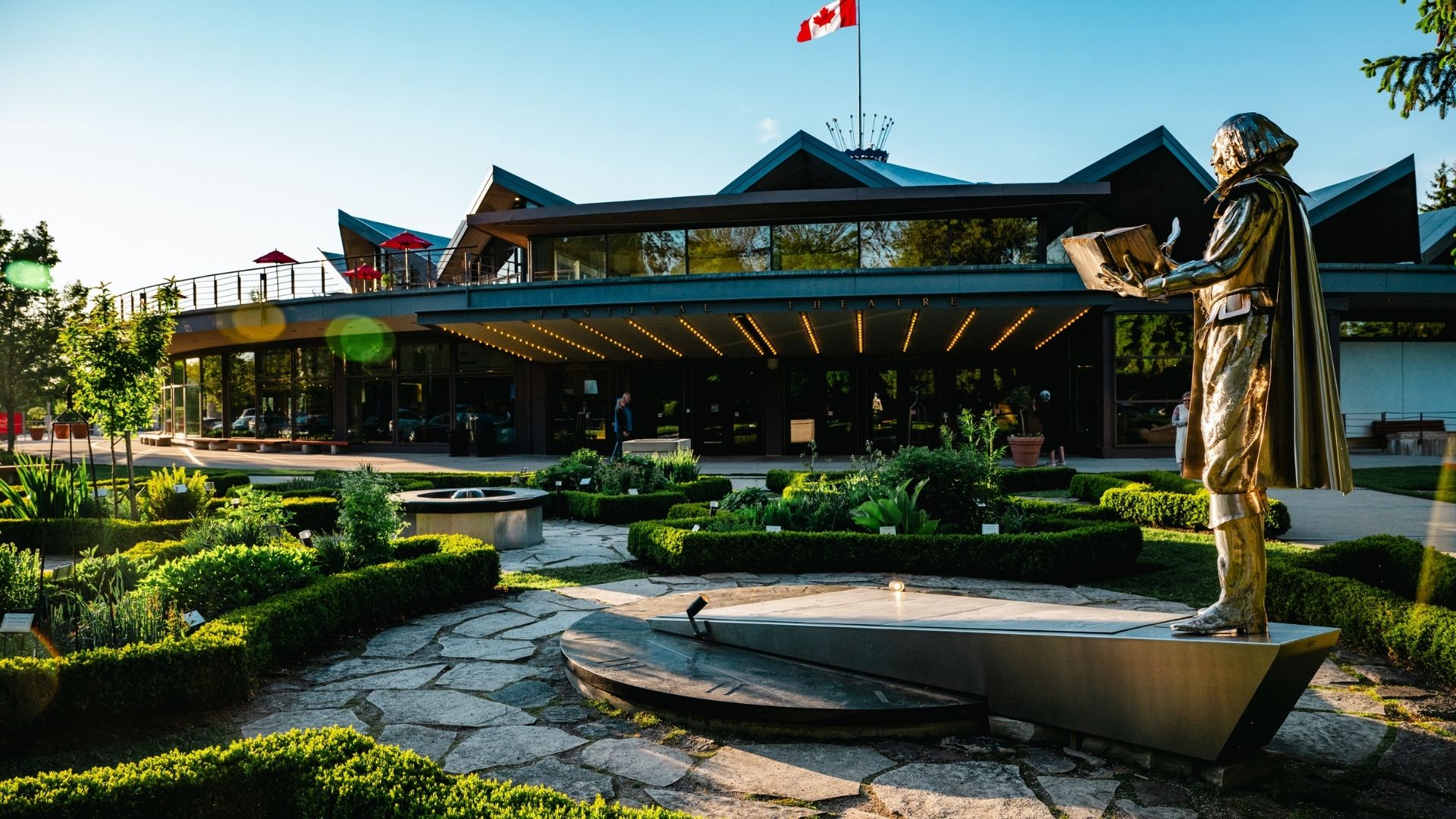 View of the outside of the Stratford Festival theatre main building with a statue of William Shakespeare in the foreground